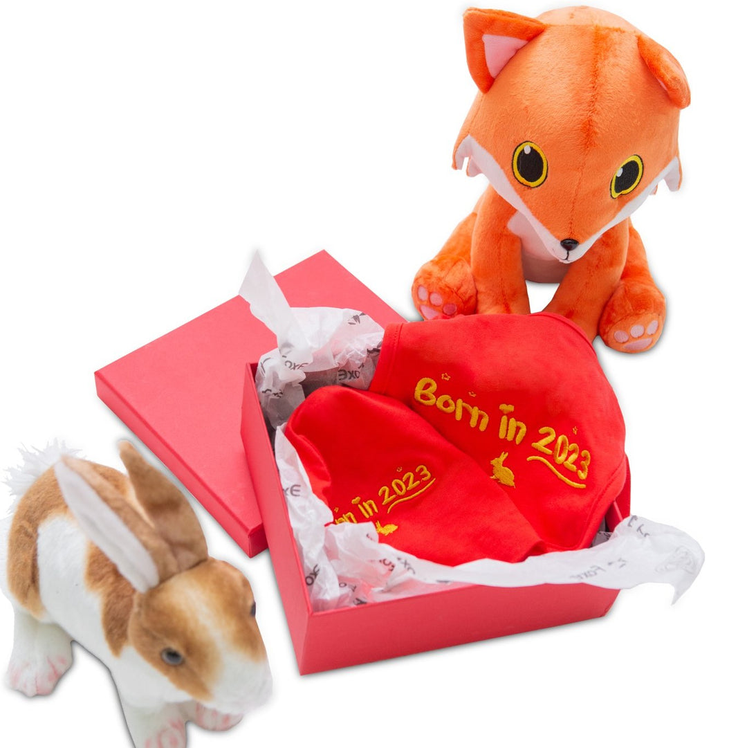 A cuddly toy fox is sitting with a cuddly toy rabbit and a Born In 2023 year of the rabbit gift set.