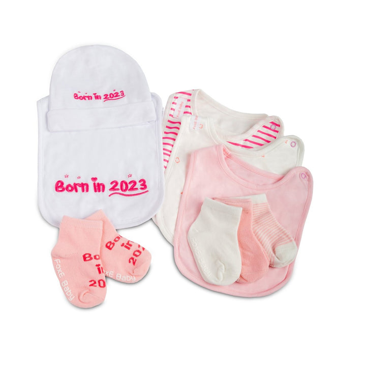 A pink Born In 2023 Gift Set including 4 bibs, 4 pairs of soft cotton socks, and a cute baby beanie.