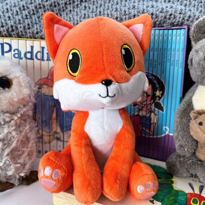 A soft Fox cuddle toy sitting with some childrens books and other soft toys.